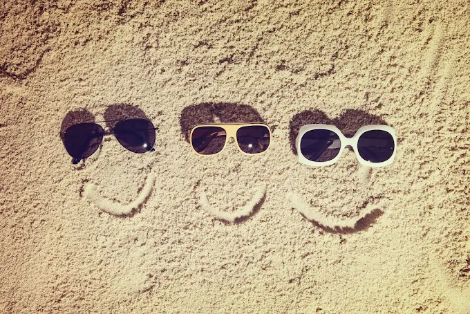 Three pairs of sunglasses on sand — Fantastic Glasses Okotoks
